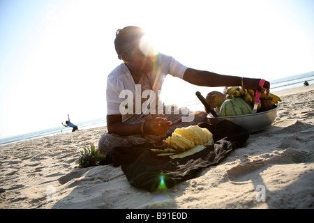 Una donna locale sellign frutta fresca tropicale ai turisti su Mobor Beach in Goa, India. Foto Stock