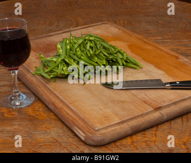 Un tagliere con jullienned fagiolini, un Coltello Santoku vegetali e un bicchiere di vino per lo chef Foto Stock