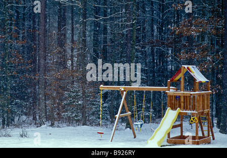 Bambini gioco all'aperto set, scheda di scorrimento, rotazione, sand box, fort, coperto con inizio inverno neve. Foto Stock