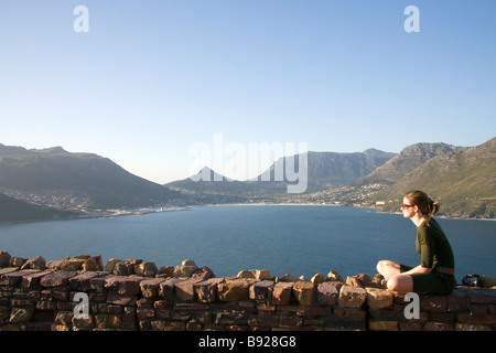 Vista di una giovane donna seduto accanto a Chapman's Peak Drive, Città del Capo, Provincia del Capo Occidentale, Sud Africa Foto Stock