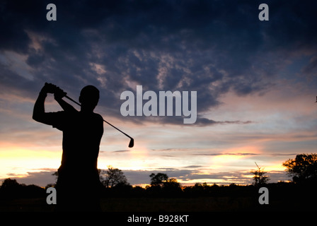 Silhouette di un giocatore di golf alla fine del suo swing in impostazione di Bushveld Riserva Moremi Botswana Foto Stock