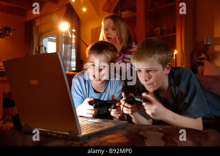 2 fratelli e sua sorella, 7, 11 e 13 anni, la riproduzione di un gioco per computer, corsa in auto, a casa. Foto Stock