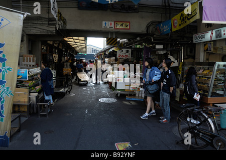 Shoppers vagare attraverso una fila di platea a Tokyo è il mercato del pesce di Tsukiji Foto Stock