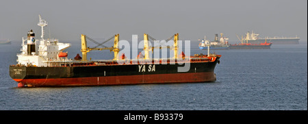 Spedizioni con foschia termica, comprese navi portarinfuse e petroliere all'ancoraggio marittimo al largo della costa del porto di Fujairah, Golfo dell'Oman, vicino allo stretto di Hormuz Foto Stock
