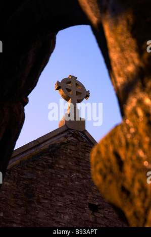 Croce di pietra sulla sommità della chiesa abbandonati a Buckfastleigh visualizzato se una finestra ad arco Devon UK Foto Stock