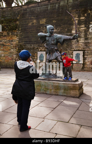 Donna di scattare una foto del suo bambino gioca su Robin Hood statua al di fuori del castello di Nottingham, Nottingham, Inghilterra, Regno Unito Foto Stock