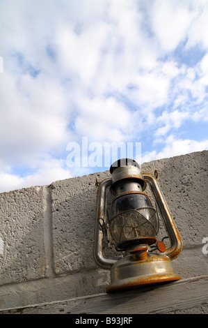 Lampada di uragano con ruggine contro una parete nella luce del pomeriggio Foto Stock