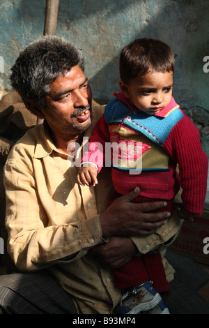 Un uomo tiene un bambino piccolo in un mercato di New Delhi, India. Foto Stock