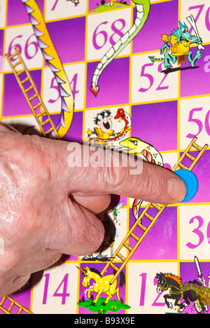 Una chiusura di una persona che muove il contatore in un gioco di serpenti & scale Foto Stock