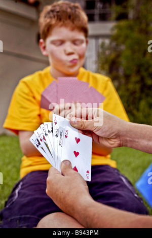 A dieci anni rosso caucasica intitolata boy valuta la sua mano come suona carte all'aperto in Laguna Niguel ca nota le carte partner Foto Stock