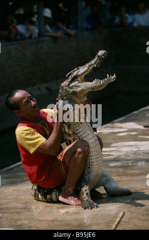 Tailandia provincia di Nakhon Pathom Bangkok Rose Garden Uomo di wrestling con coccodrillo e guardare la gente da dietro barrier Foto Stock