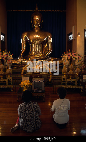 Il sud della Thailandia Bangkok Wat Traimit Tempio del Buddha d'oro di due donne inginocchiato in preghiera di fronte al Buddha. Foto Stock