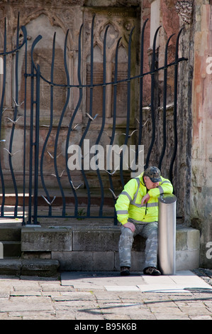 Uomo che guarda annoiato e premuto in una giacca di sicurezza nelle rovine di santa chiesa Rood in Southampton Foto Stock