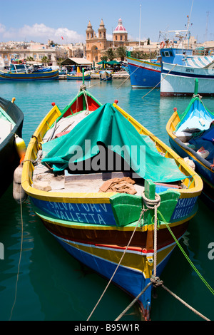 MALTA Marsaxlokk Harbour barche colorate e la chiesa di Nostra Signora del Rosario nella costa sud del villaggio di pesca Foto Stock