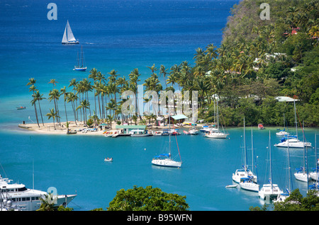 WEST INDIES Caraibi St Lucia Castries Marigot Bay Yacht al di ancoraggio al di là di piccole palme da cocco alberata di spiaggia Beach Club Foto Stock