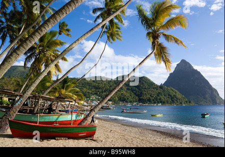 WEST INDIES Caraibi St Lucia Soufriere Pitons barche di pescatori sulla spiaggia fiancheggiato da palme di cocco con città e Petit Piton Foto Stock
