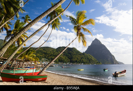 West Indies Caraibi St Lucia Soufriere barche di pescatori sulla spiaggia fiancheggiato da palme di cocco. Città vulcanica e al di là di Pitons Foto Stock