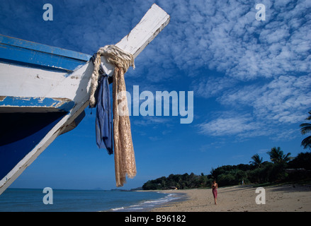 Tailandia Krabi Koh Lanta Yai Relax Bay Beach con turista femminile raccogliendo conchiglie sulla spiaggia con la prua della barca in primo piano Foto Stock