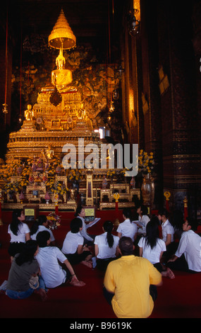 Il sud della Thailandia Bangkok Wat Pho tempio principale sala di preghiera con un gruppo di studenti di Thai e maestro insediato prima di Buddha d'Oro Foto Stock