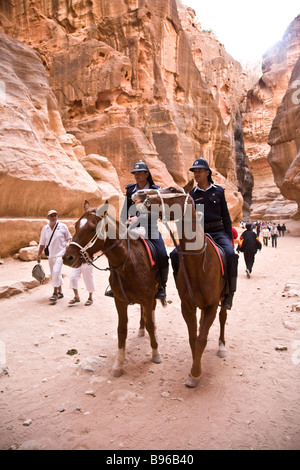 Colpo di polizia turistica a cavallo rendendo il viaggio attraverso il Siq di Petra sulla strada verso il ministero del tesoro. Foto Stock