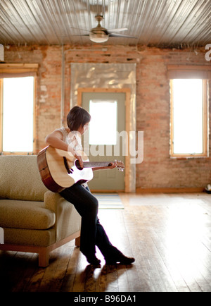 Giovane donna a suonare la chitarra in spazi urbani Foto Stock