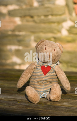 Grubby abbandonato orsacchiotto di peluche su un tavolo di legno Foto Stock