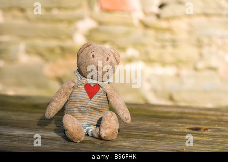 Grubby abbandonato orsacchiotto di peluche su un tavolo di legno Foto Stock