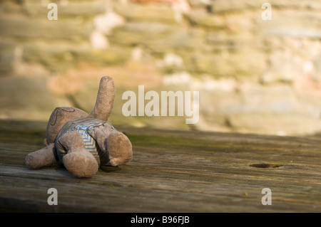 Grubby abbandonato orsacchiotto di peluche su un tavolo di legno Foto Stock