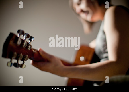 Giovane donna a suonare la chitarra Foto Stock