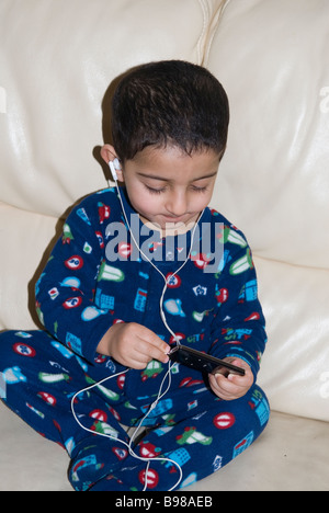 Little Boy ascoltando musica su ipod nano Foto Stock