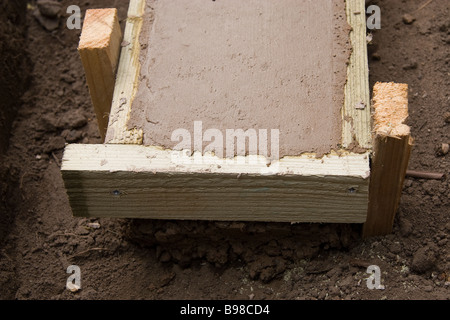 La figura mostra che il calcestruzzo appigli per un piccolo giardino parete ha penetrato abbastanza profondo per passare al di sotto delle casseforme Foto Stock