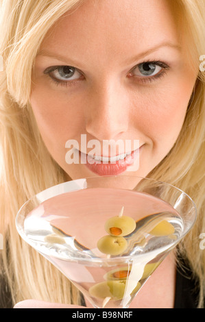 Close-up di un attraente donna bionda sorseggiando un bicchiere di martini Foto Stock