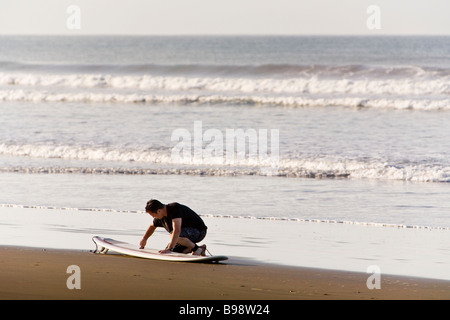 Ceretta uomo la sua tavola da surf sulla riva di Dominical, Costa Rica. Foto Stock