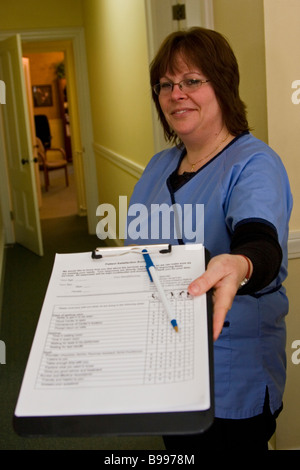 Donna, receptionist dell'ufficio del medico consegna modulo paziente negli appunti Foto Stock