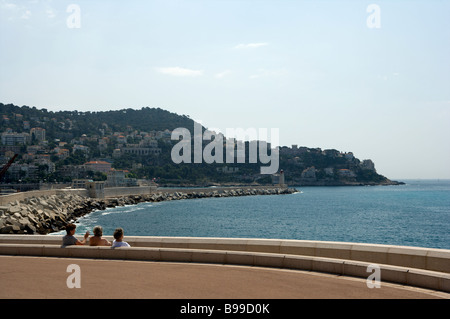 Tre turisti femmina guardare oltre il punto di vista della Cote d Azur nella luce del sole da un banco e area di visualizzazione. Foto Stock