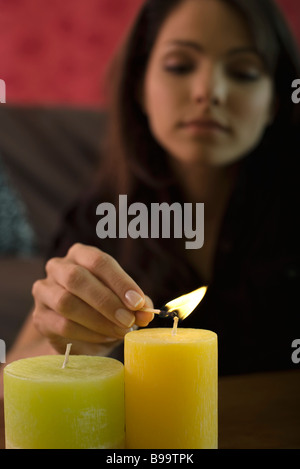 Giovane donna accendendo candele, la messa a fuoco su oggetti in primo piano Foto Stock