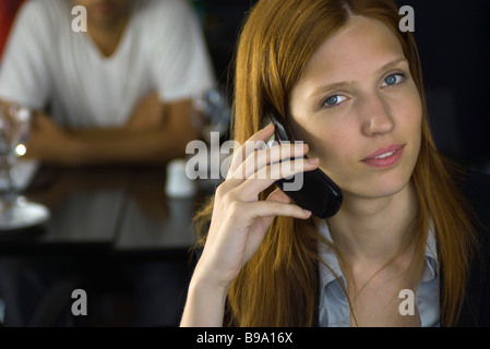 Donna che mantiene il telefono cellulare all'orecchio, sorridente in telecamera Foto Stock