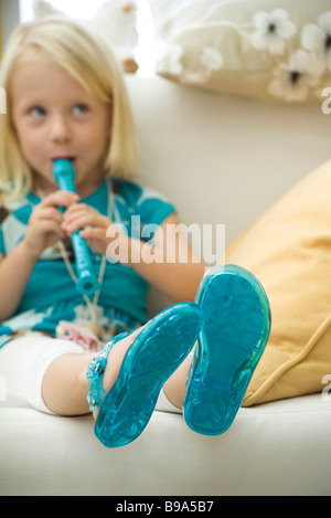 Poco ragazza seduta sul divano, registratore di riproduzione Foto Stock