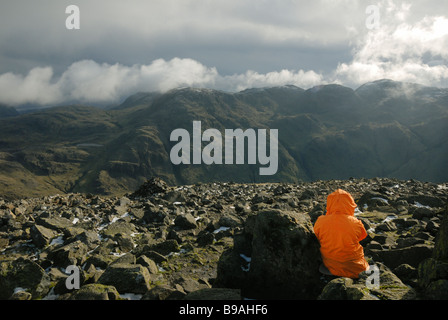 Walker nuvole orologi scremare oltre il vertice di Scafell Pike dal grande timpano, Cumbria Regno Unito Foto Stock