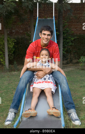 L'uomo gioca con sua figlia in una diapositiva Foto Stock