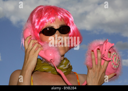 Donna con parrucca rosa in possesso di un telefono rosa Foto Stock