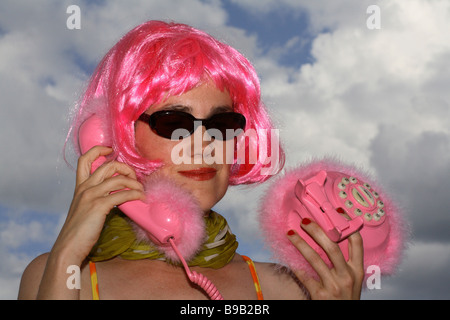 Donna con parrucca rosa in possesso di un telefono rosa Foto Stock