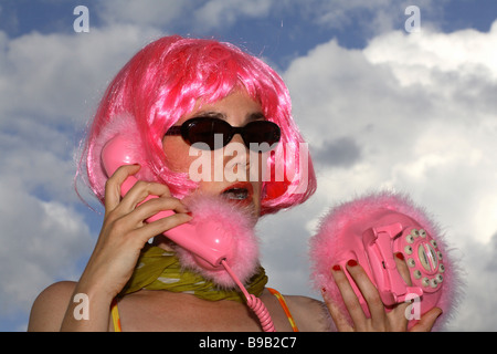 Donna con parrucca rosa in possesso di un telefono rosa Foto Stock