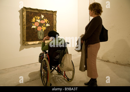 Una persona con disabilità in sedia a rotelle vede una mostra d'arte a Tel Aviv Israele Foto Stock
