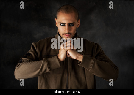 Bello ispanica africana guy accigliata con forte mad macho espressione e occhi scuri nel giubbotto verde e le mani in un pugno Foto Stock