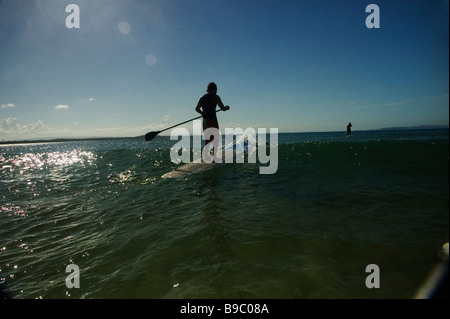 Standup surfer paddeling fuori Foto Stock