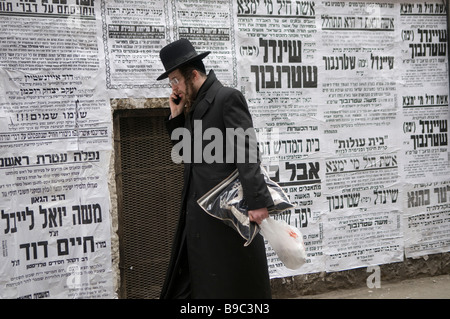 L'ebreo ortodosso passa accanto ai poster di Pashkvilim che servono come annunci della comunità nel quartiere Mea Shearim Haredi a Gerusalemme Israele Foto Stock