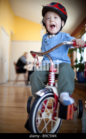 Bambino a cavallo di un triciclo intorno alla casa Foto Stock