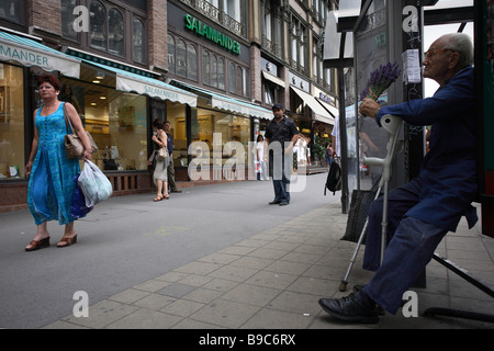 Un uomo vecchio con le stampelle che vendono fiori sulla street, Budapest, Ungheria Foto Stock