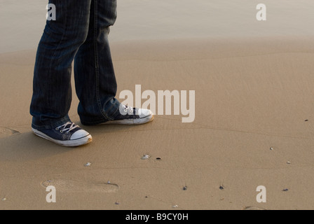 La sezione inferiore di un uomo che indossa converse formatori scarpe camminando dalla spiaggia di Beirut Libano Medio Oriente Foto Stock